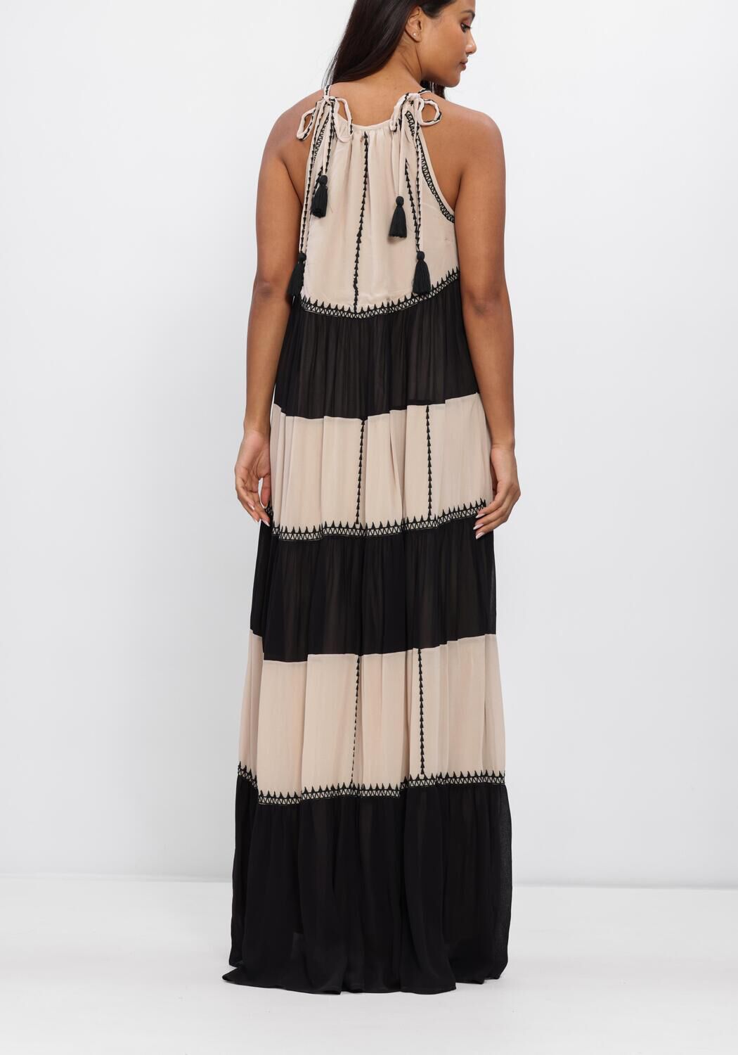 Pink Baby beige and black tassel-tie tiered maxi dress with flowing fabric and tiered layers, styled for a boho look.