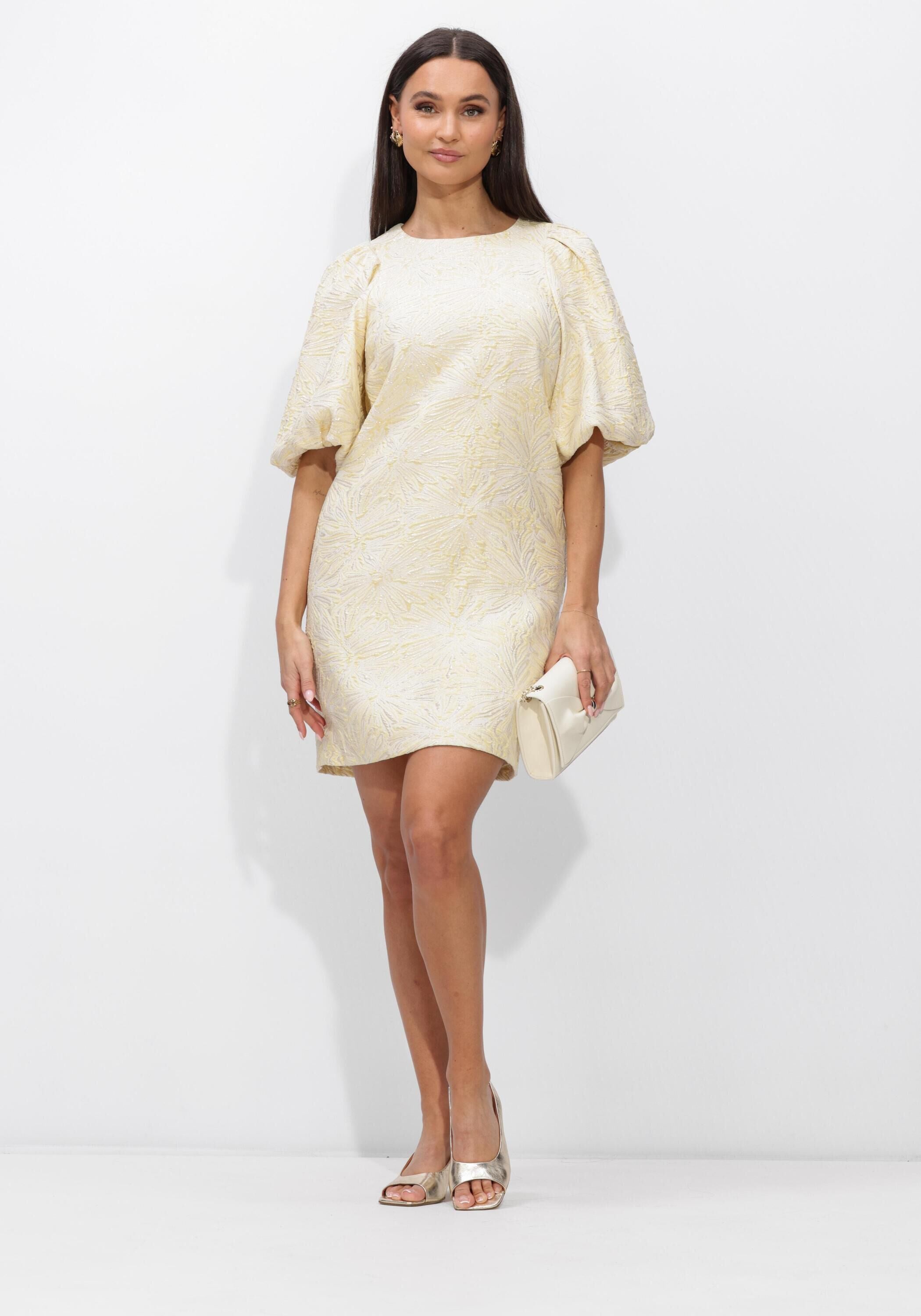 Pink Baby Sabelle textured puff sleeve mini dress in cream with ruffled details and a fitted silhouette, displayed on a hanger.