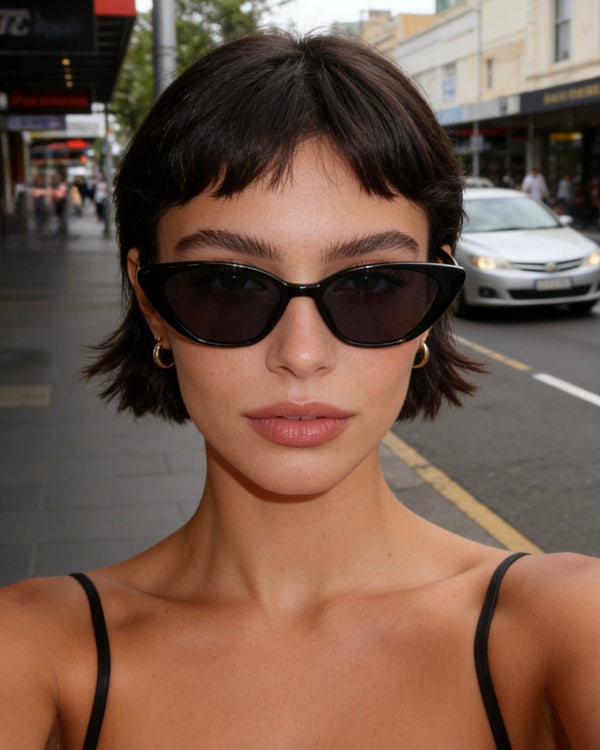 Pink Baby The Juno black sunglasses with stylish frame and tinted lenses, resting on a white surface.