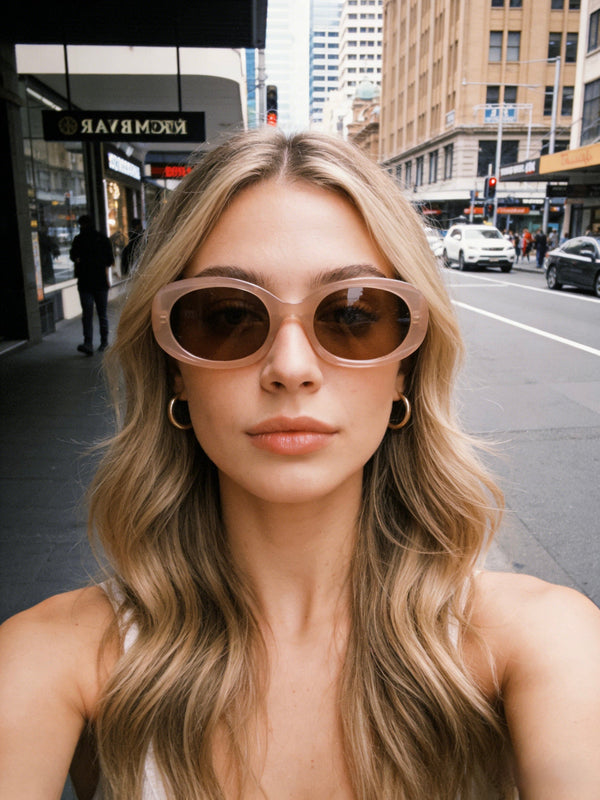 Pink Baby Flynn pink sunglasses with rounded frames and tinted lenses, resting on a white surface.