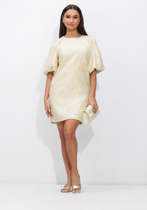 Pink Baby Sabelle textured puff sleeve mini dress in cream with ruffled details and a fitted silhouette, displayed on a hanger.