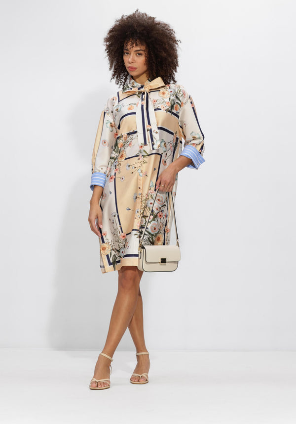 Pink Baby Lucienne floral scarf-tie shirt dress in champagne beige with floral pattern, featuring a classic collar and long sleeves.