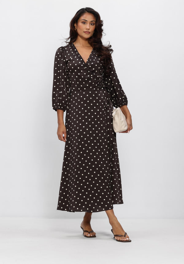 Pink Baby Vivi polka dot wrap midi dress in chocolate brown with long sleeves and a fitted waist, styled with a flowing skirt.