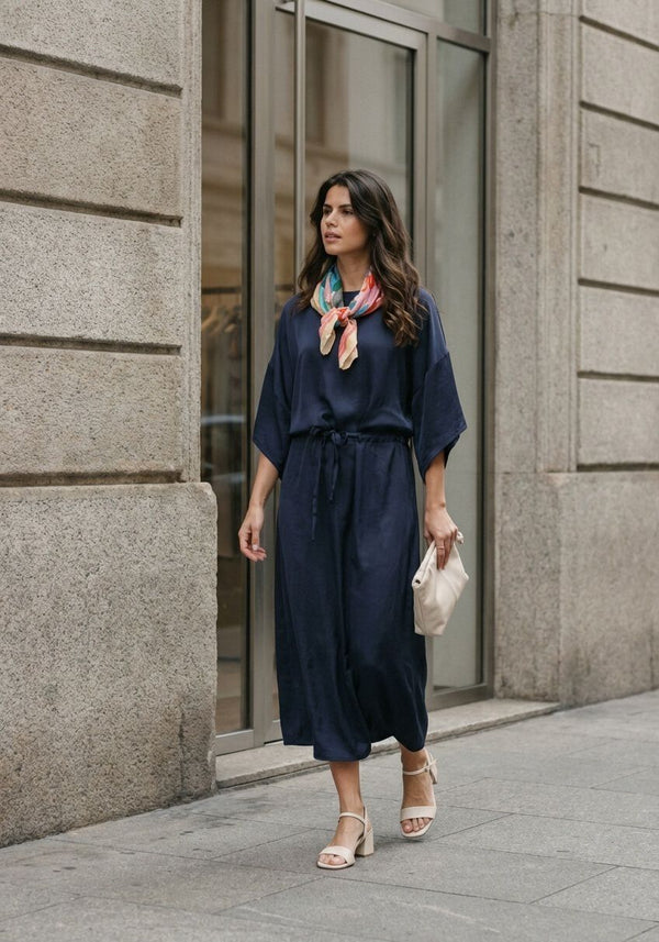 Navy Noemi satin tie-waist midi dress by Pink Baby, shown on a hanger with smooth fabric and elegant design.