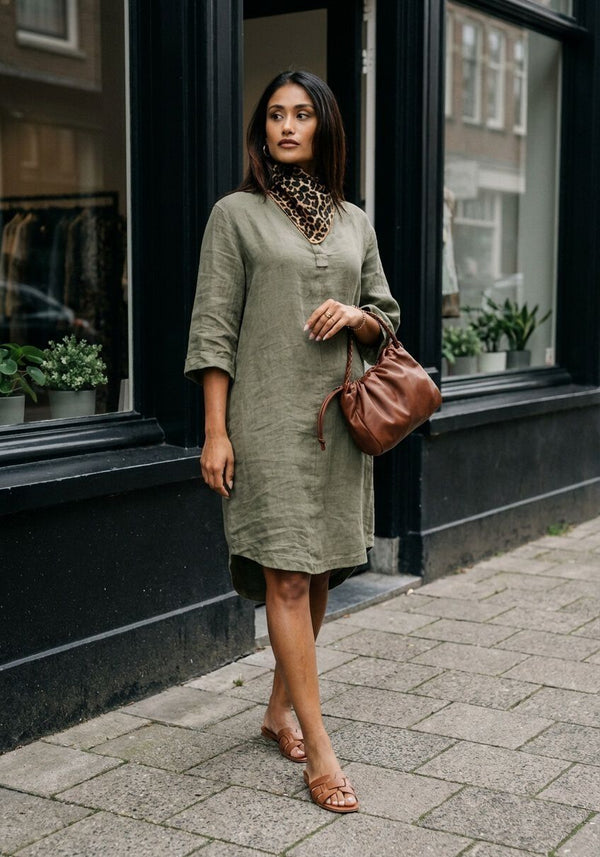 Pink Baby Sabrina linen tunic midi dress in olive green, shown on a hanger with a close-up of fabric texture and details.